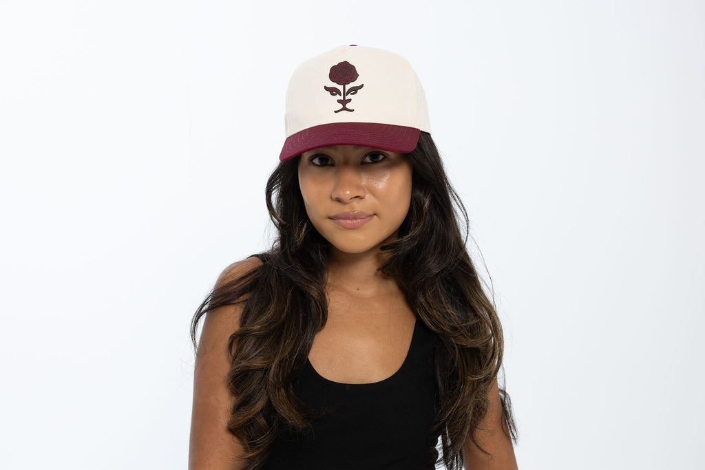Woman wearing a white cap with a red brim and logo on a white background