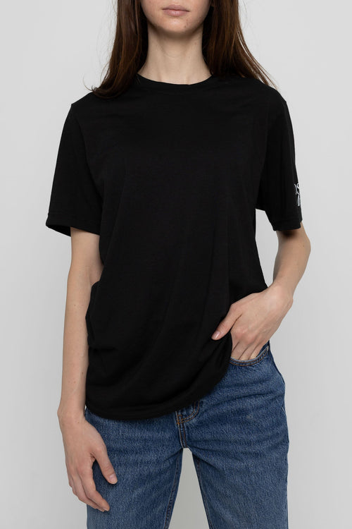 Person wearing a black t-shirt and blue jeans on a plain background