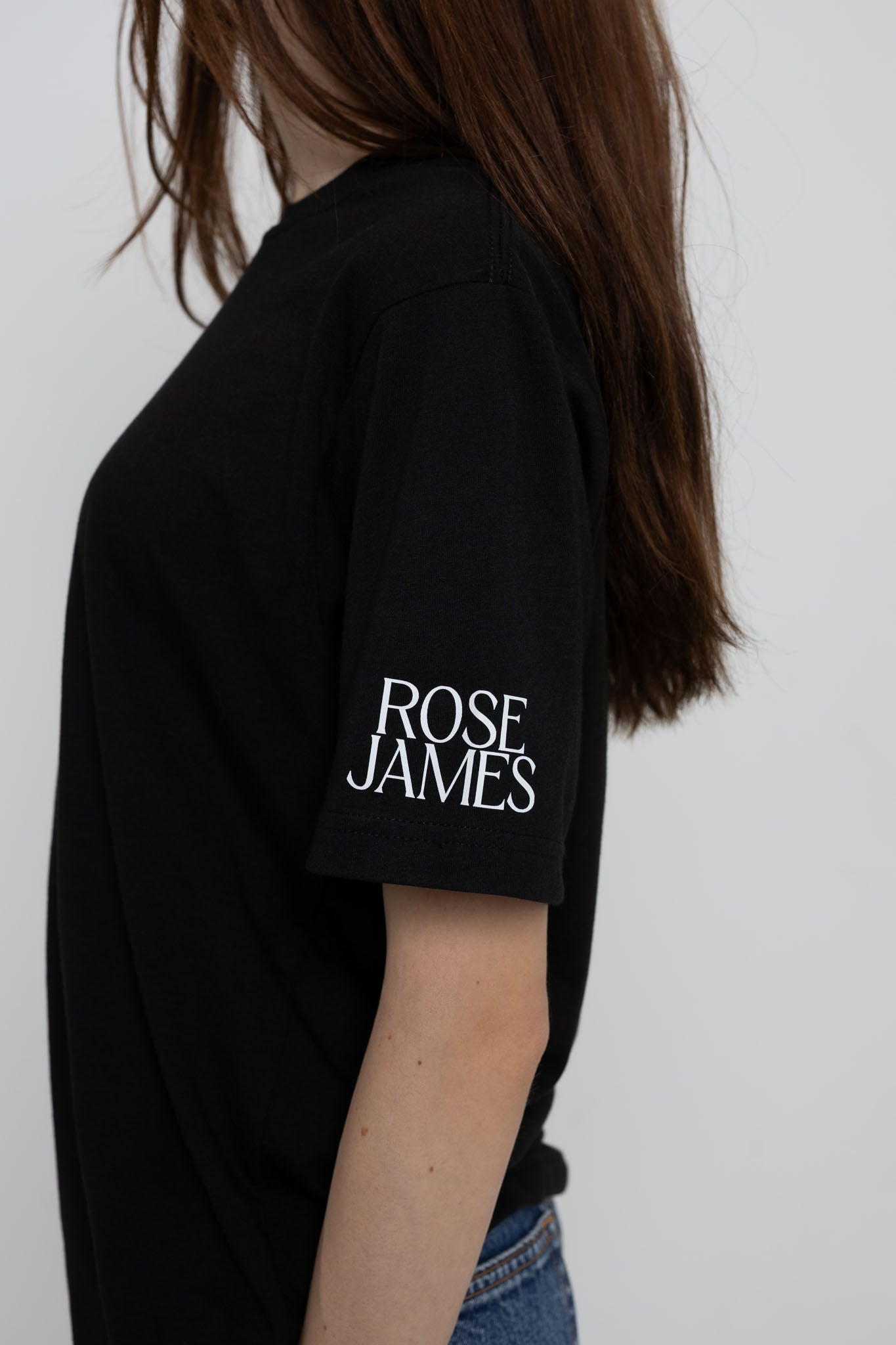 Person wearing a black t-shirt with 'ROSE JAMES' text on a plain background