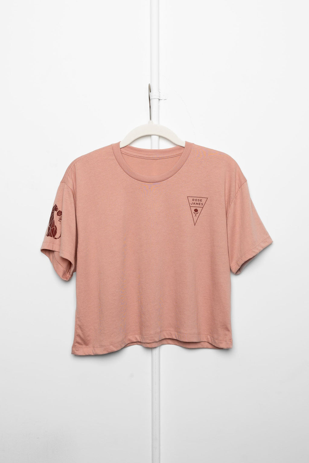 Pink t-shirt with a logo on a hanger against a white background