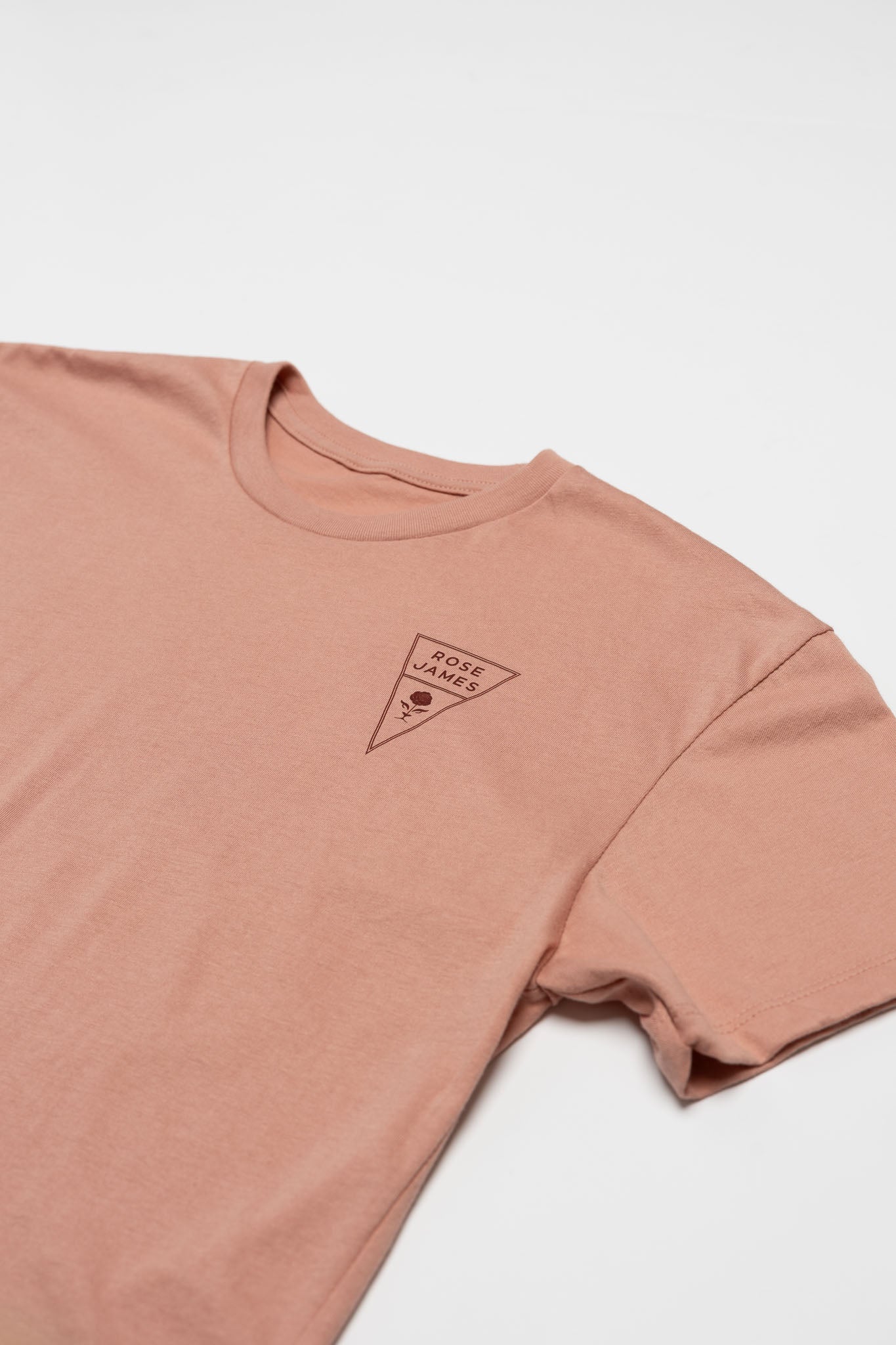 Pink t-shirt with a small logo on a white background