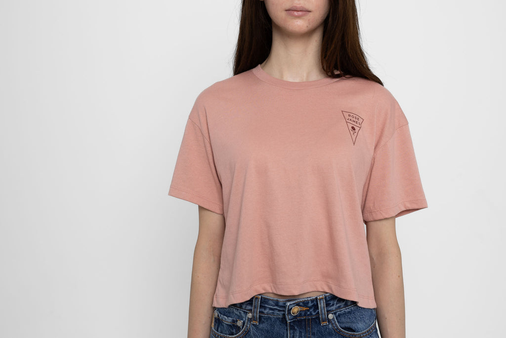 Person wearing a pink t-shirt with a logo on a white background
