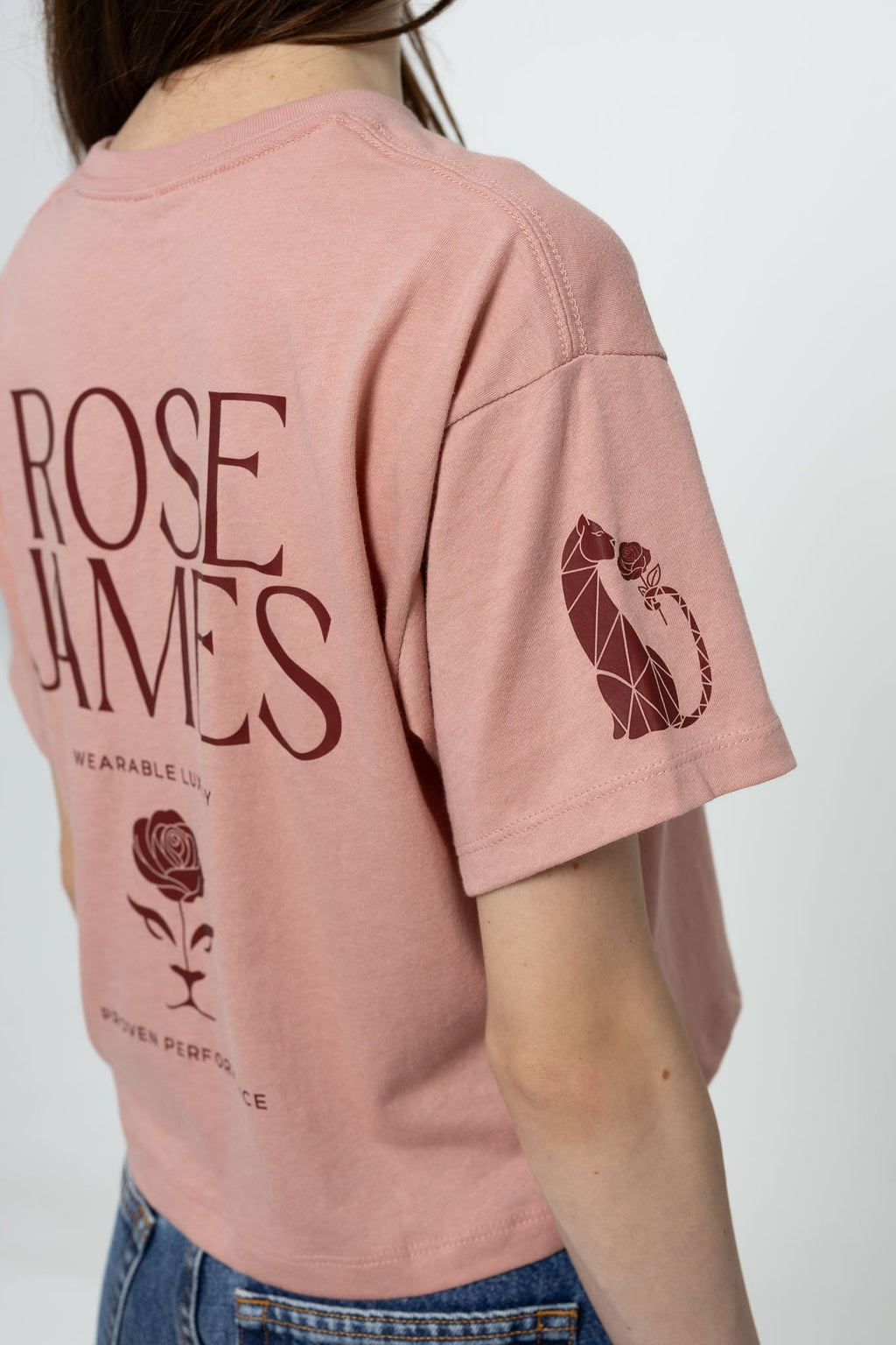 Person wearing a pink t-shirt with 'Rose James' branding and graphics on a plain background